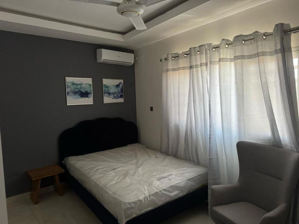 a bedroom with a bed and a chair and a window at Apartment building in Salagi in Sukuta