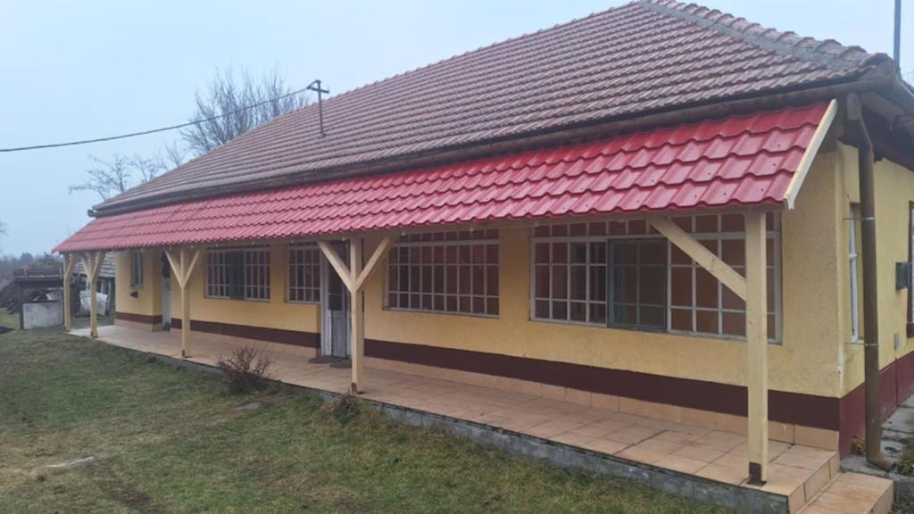 a yellow and red house with a red roof at Charming farmhouse in Poroszl in Hungary on the Tisza Lake in Poroszló