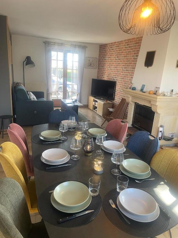 - une table avec des assiettes et des verres dans le salon dans l'établissement Le Repos de Sainte Mère Église, à Sainte-Mère-Église