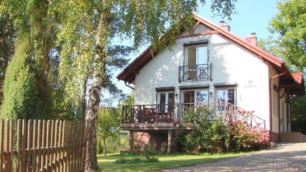 een wit huis met een hek ervoor bij Dom nad jeziorem Lewinko Kaszuby in Pobłocie
