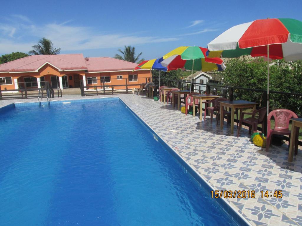 una piscina con sombrillas, mesas y sillas en Jamaica Inn Guest House en Botianaw