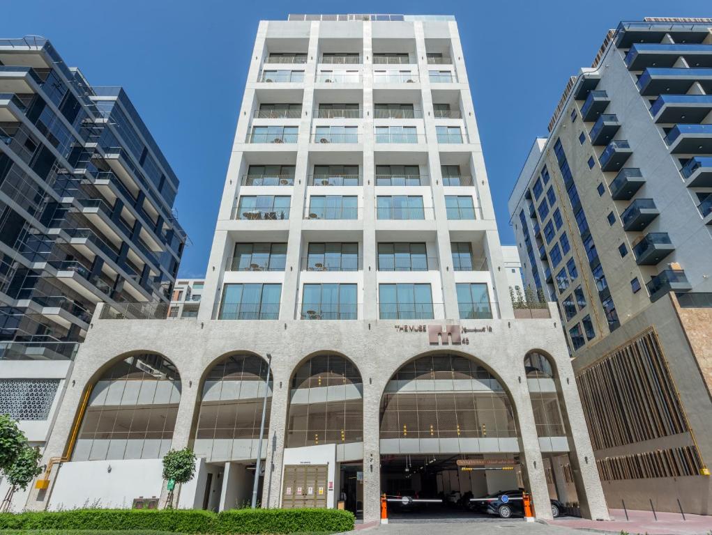 a tall white building with two tall buildings at Mood Living 45 in Dubai