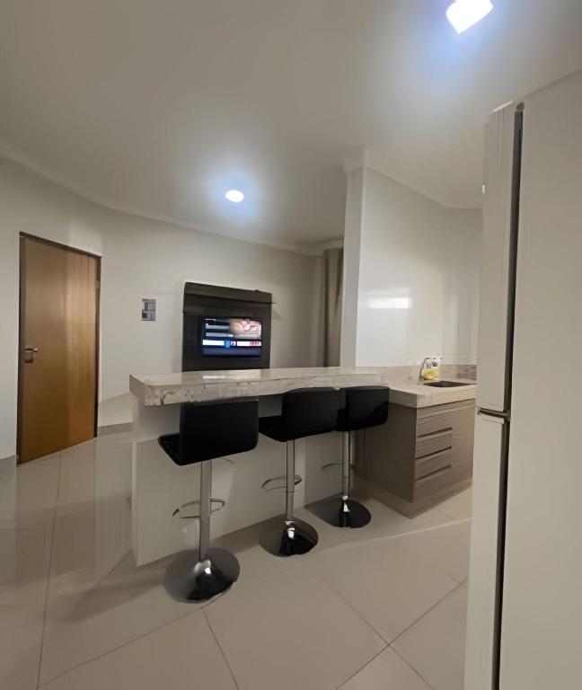 a kitchen with two bar stools and a television at Residencial Algarve in Patos de Minas