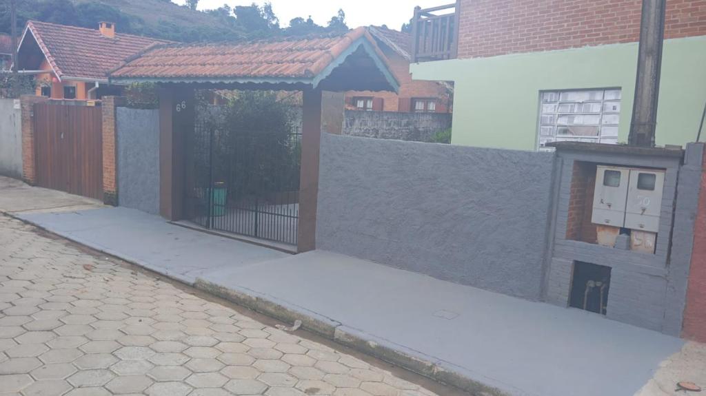 a street with a fence and a gate with a building at Chalé Fernandes in Monte Verde