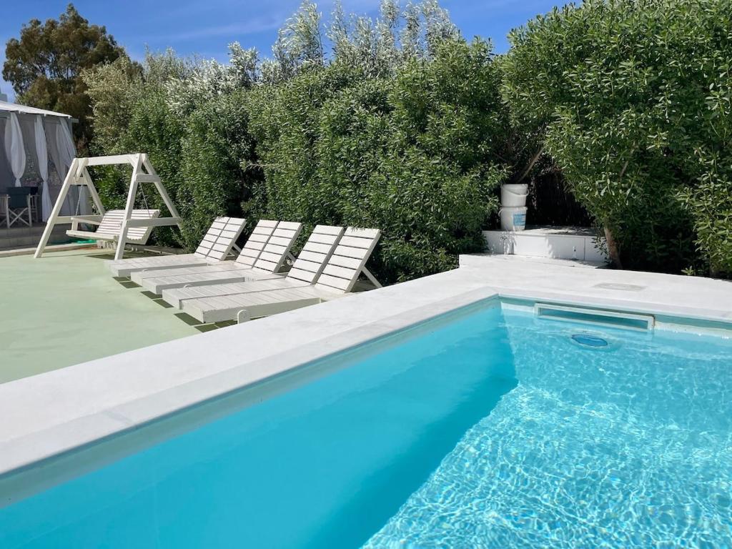 a swimming pool with two white chairs next to it at AIR, Oneiropagida, Aegina in Vathí
