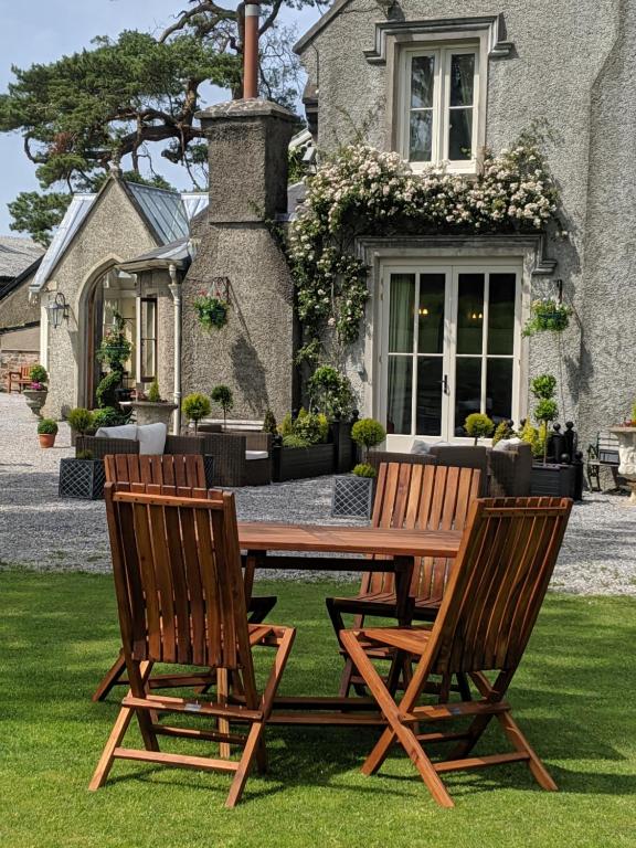 two wooden chairs and a wooden table in front of a house at Parc-Le-Breos House in Penclawdd