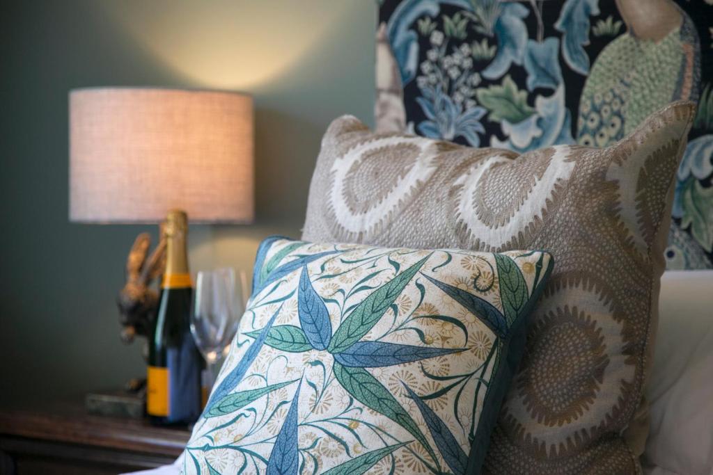 a pillow on a chair with a lamp and a bottle of wine at Parc-Le-Breos House in Penclawdd