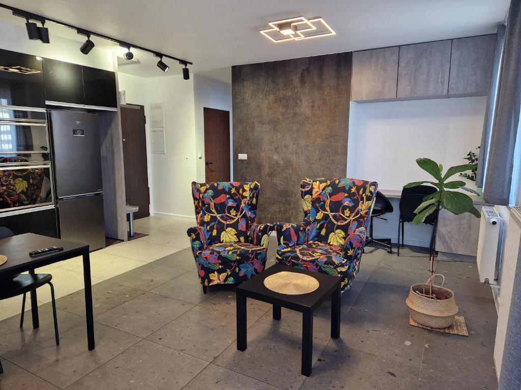 ein Wohnzimmer mit zwei Stühlen und einem Tisch in der Unterkunft Apartament Katowice Tysiąclecie in Kattowitz