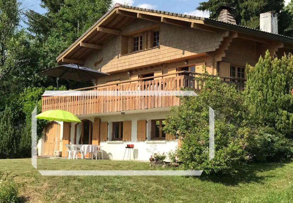 une maison en bois avec un parasol vert devant elle dans l'établissement Charmant appartement avec jardin et magnifique vue, à Saint-Jean-de-Sixt
