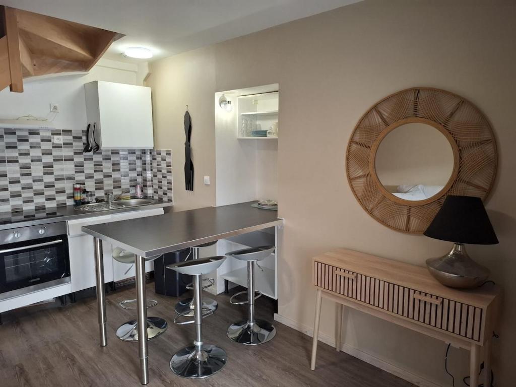 - une cuisine avec une table, des tabourets et un miroir dans l'établissement Duplex en centre-ville, à Fontainebleau