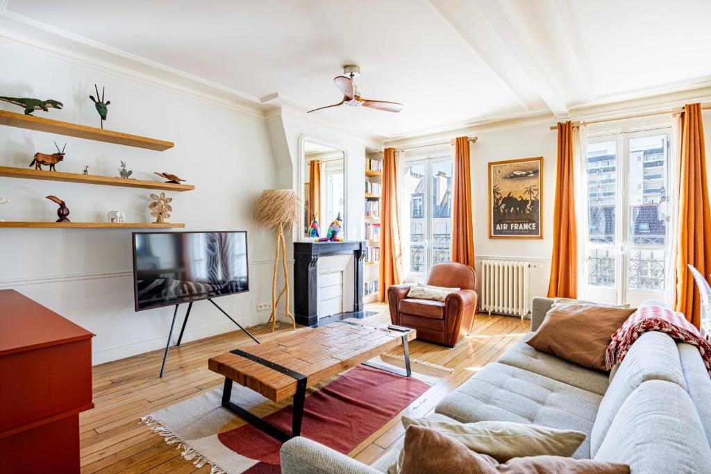 un salon avec un canapé et une télévision dans l'établissement Appartement Collette - Welkeys, à Paris