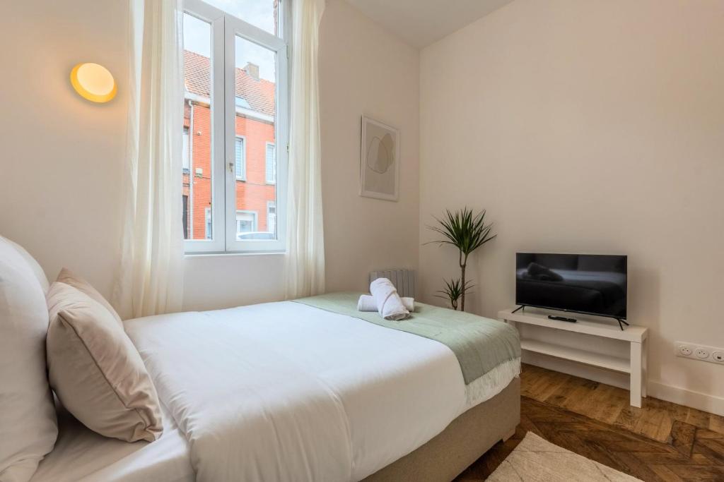 une chambre blanche avec un lit et une télévision dans l'établissement Studio fonctionnel pour une personne, proche tram, à Tourcoing