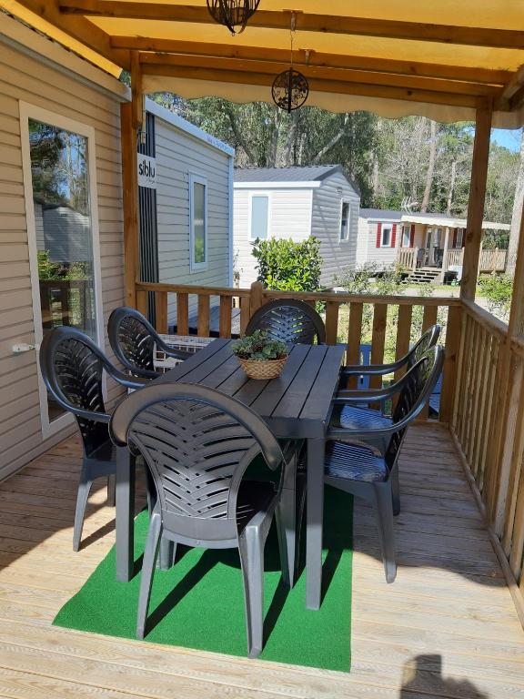 un patio avec une table et des chaises sur une terrasse dans l'établissement Mobilhome au bassin d'Arcachon, à Lège-Cap-Ferret