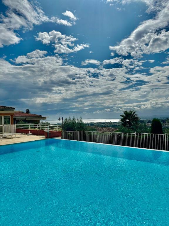 une grande piscine bleue avec un ciel nuageux dans l'établissement Le Dolce Vita, à Nice