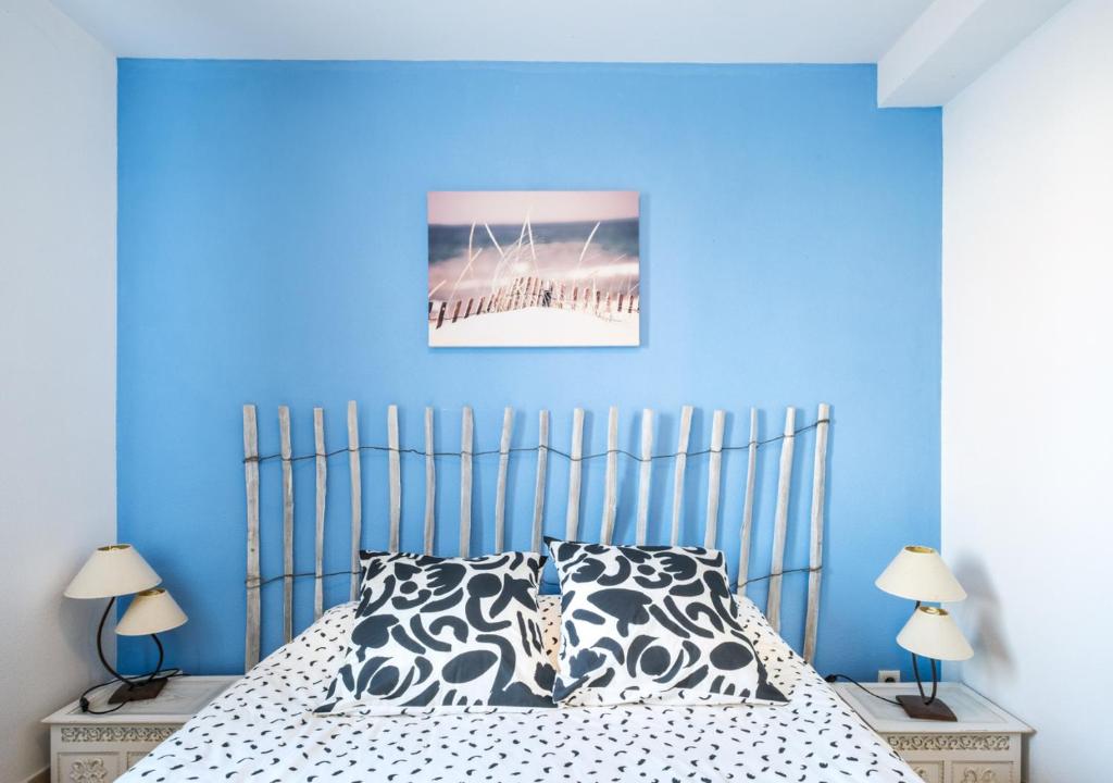 une chambre avec un lit avec un mur bleu dans l'établissement Confort & Nature près du Lac, à Biscarrosse