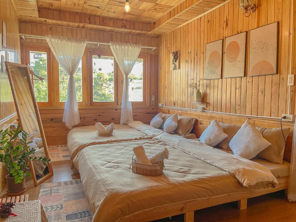 ein großes Bett in einem Zimmer mit Holzwänden und Fenstern in der Unterkunft Đà Lạt 2019 homestay in Ấp Phước Thánh