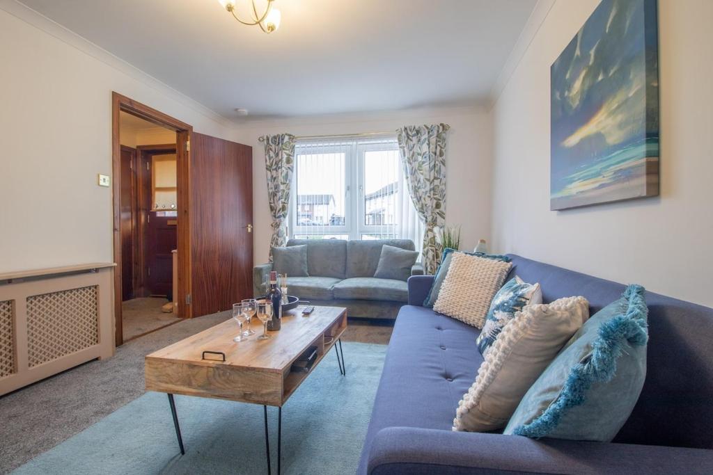 een woonkamer met een blauwe bank en een tafel bij Glasgow, spacious, 2 bed with parking in Garthamlock