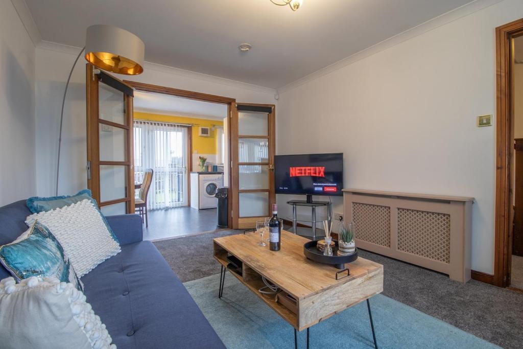 a living room with a blue couch and a table at Glasgow, spacious, 2 bed with parking in Garthamlock