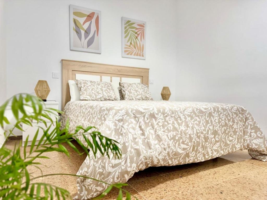 a bedroom with a white bed with pillows and a plant at Brisas de Sardina Apartment in Sardina