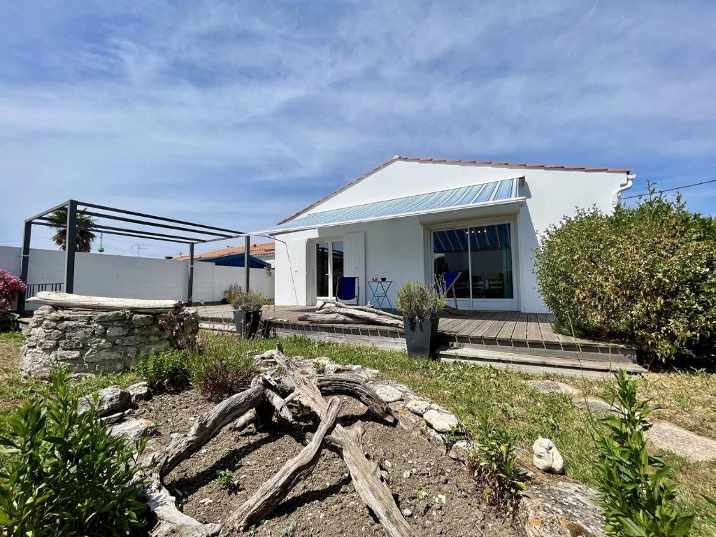 une maison blanche avec une pile de bûches devant elle dans l'établissement Maison 4 pièces 8 couchages Saint Pierre d'Oléron SPO000-820, à Saint-Pierre-dʼOléron