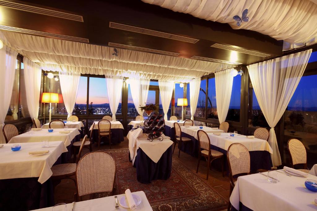 ein Restaurant mit weißen Tischen, Stühlen und Fenstern in der Unterkunft Relais La Corte di Bettona in Bettona