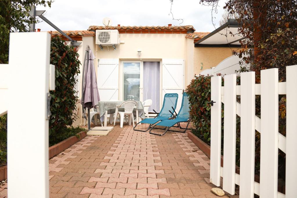 d'une terrasse avec une clôture blanche et des chaises bleues. dans l'établissement Saint Cyprien jolie maison climatisee, à Saint-Cyprien