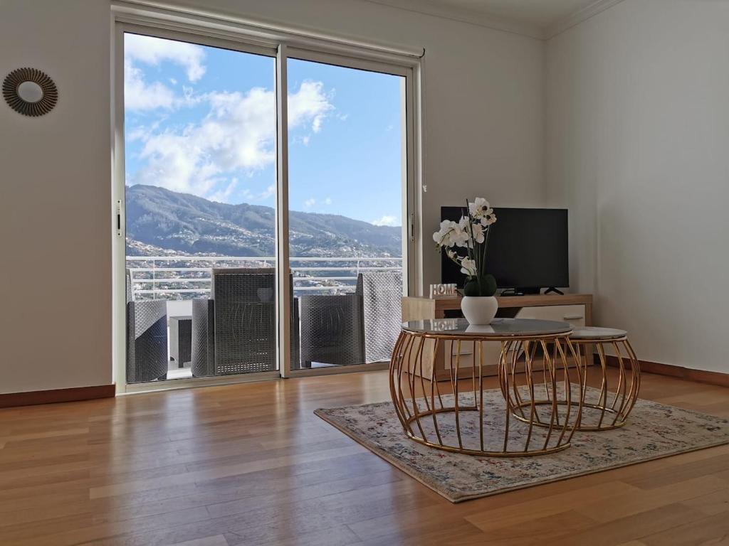 ein Wohnzimmer mit Tisch und großem Fenster in der Unterkunft Pico Barcelos - Funchal in Funchal