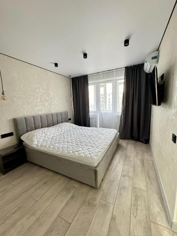 una camera da letto con un letto e un pavimento in legno di 1 комнатная квартира город Экибастуз a Ekibastuz