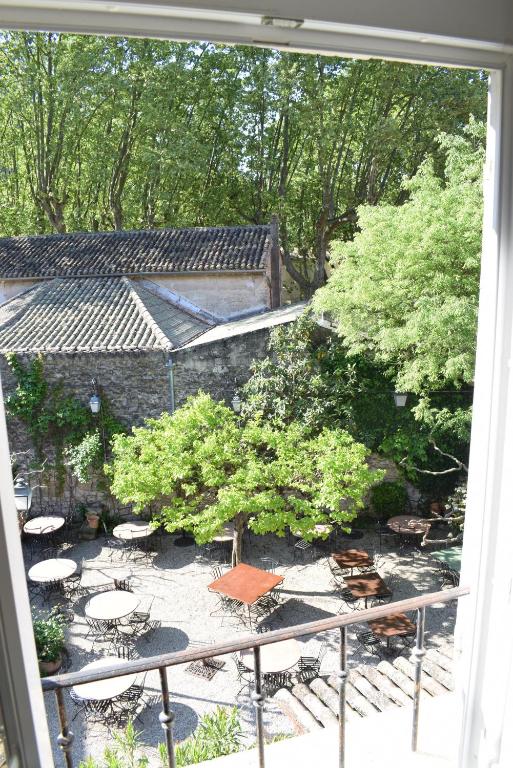 Elle offre une vue sur un jardin doté de tables et de chaises depuis sa fenêtre. dans l'établissement La Figuiere Fontaine de Vaucluse, à Fontaine-de-Vaucluse