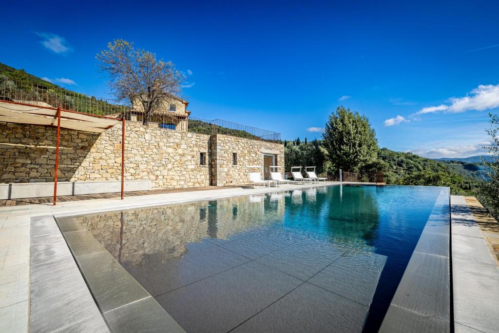 una piscina infinita frente a un edificio de piedra con una casa en YD exclusive design villa Agati, en Castiglion Fiorentino