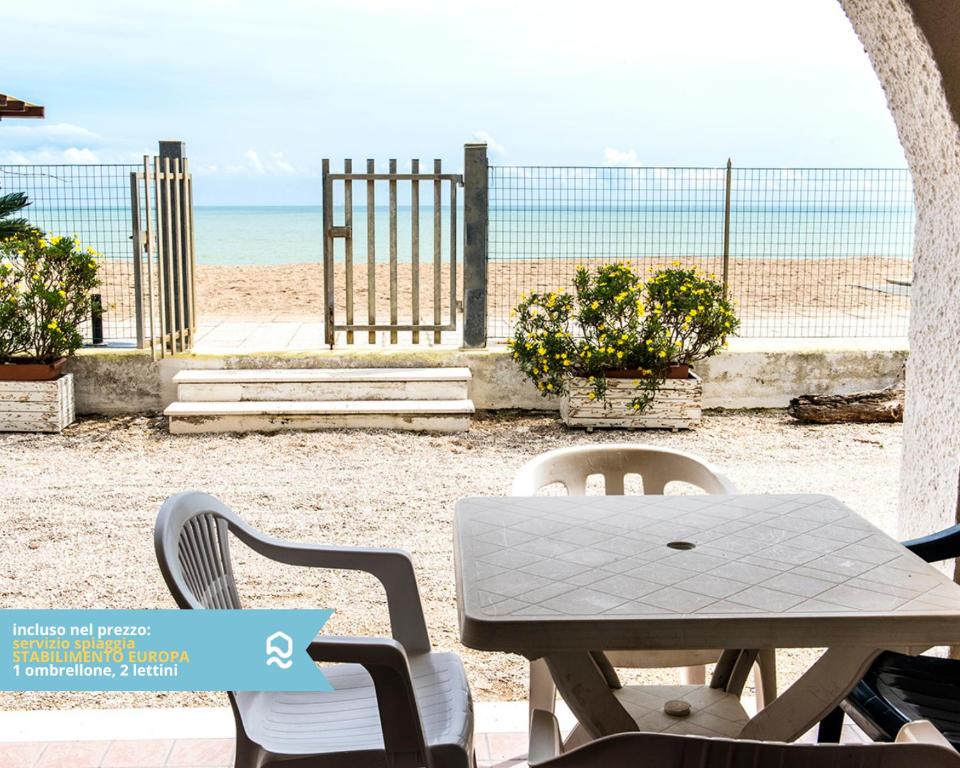 a table and chairs with a view of the beach at RS315 - Marcelli, bilocale in residence fronte mare in Marcelli