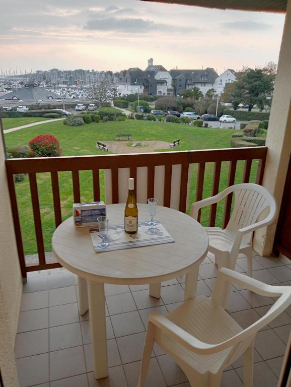 - une table avec une bouteille de vin et 2 chaises sur un balcon dans l'établissement Résidence des argonautes, à Arzon