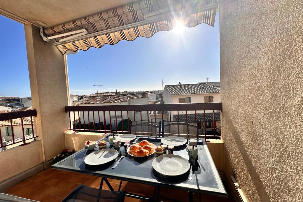 une table avec des assiettes de nourriture sur un balcon dans l'établissement L'Olivier, au Grau-du-Roi
