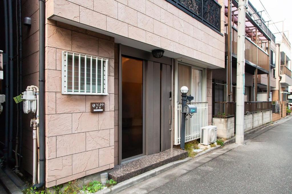 un edificio in mattoni rosa con una porta su una strada di 015T Y's INN 有客 瑞江 瑞江駅まで徒歩6分新宿まで乗換なし36分 3階建貸切 大人数向け ドンキそば a Tokyo