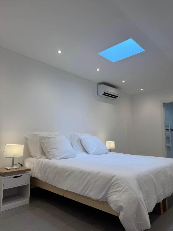 une chambre avec un lit avec des draps blancs et une fenêtre dans l'établissement UNIQUE - Rez de jardin neuf - 10 min du Palais des Festivals, à Cannes