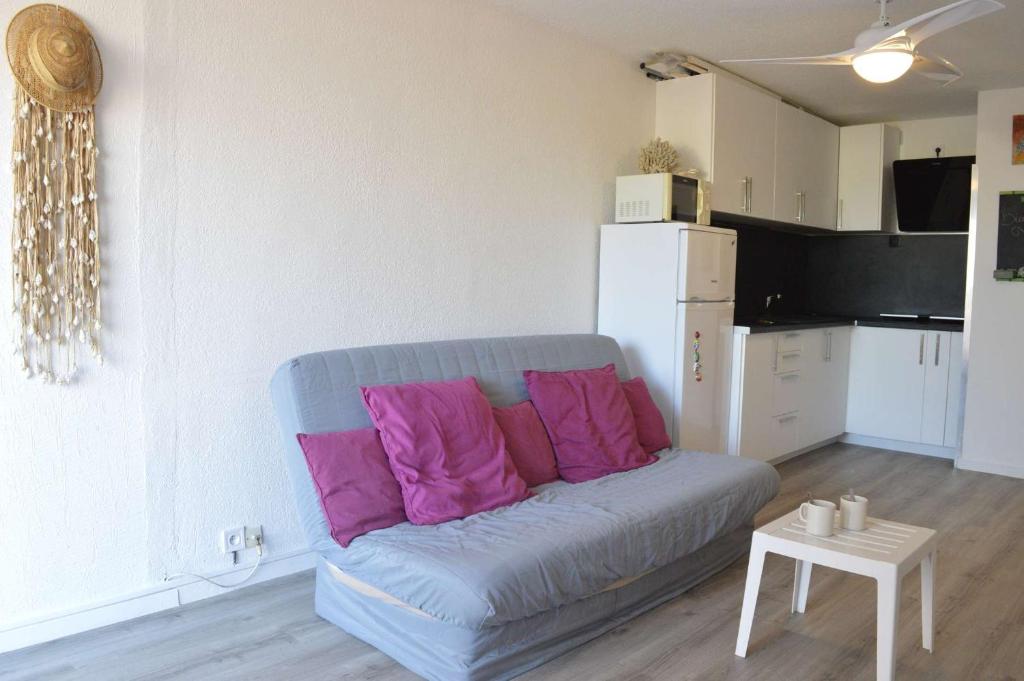 - un canapé avec des oreillers roses dans le salon dans l'établissement Appt Studio cabine 4 couchages CAP D'AGDE CT455-137, au Cap d'Agde