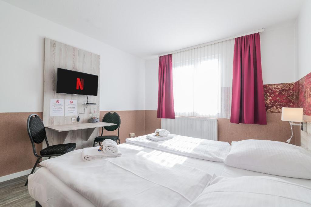 Una habitación de hotel con dos camas y una ventana. en Hotel Café Galerie I Hannover-Garbsen I Free Parking, en Garbsen