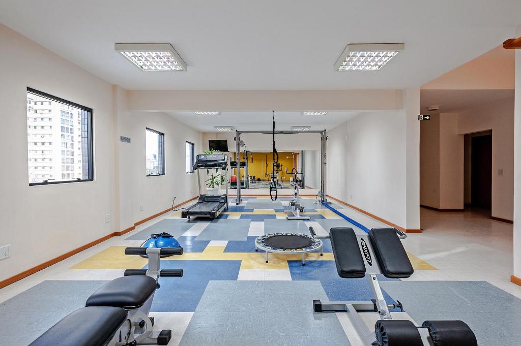 a gym with several treadmills and machines in a room at Slim Curitiba Alto da XV in Curitiba