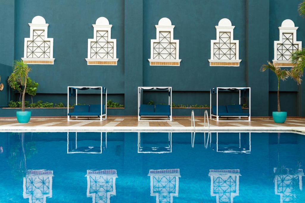 a swimming pool with blue chairs in front of a blue wall at Catalonia Santo Domingo in Santo Domingo