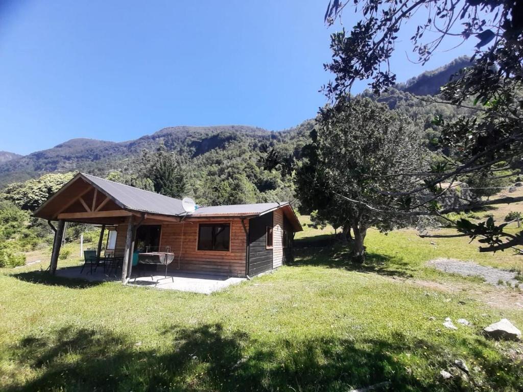 a cabin in a field with mountains in the background at Cabaña Vista Hermosa 6 Personas Conaripe in Panguipulli