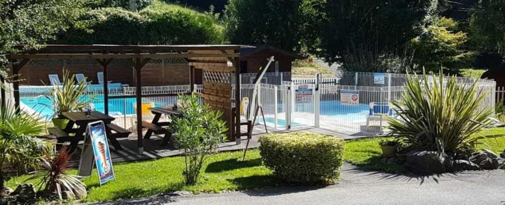 un parc avec une piscine et un pavillon dans l'établissement Camping 3 étoiles - Piscine - ccbaddh, à Louvie Juzon