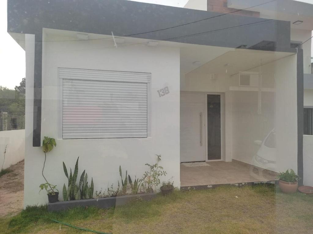 Una casa blanca con una ventana y algunas plantas. en Casa perto da Praia do Laranjal, en Pelotas