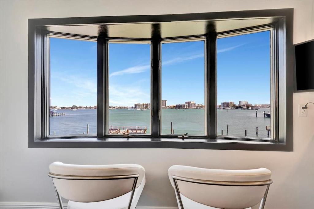 two chairs in front of a window with a view of the water at The Aura a Luxury Waterview Condo & heated pool in Clearwater Beach