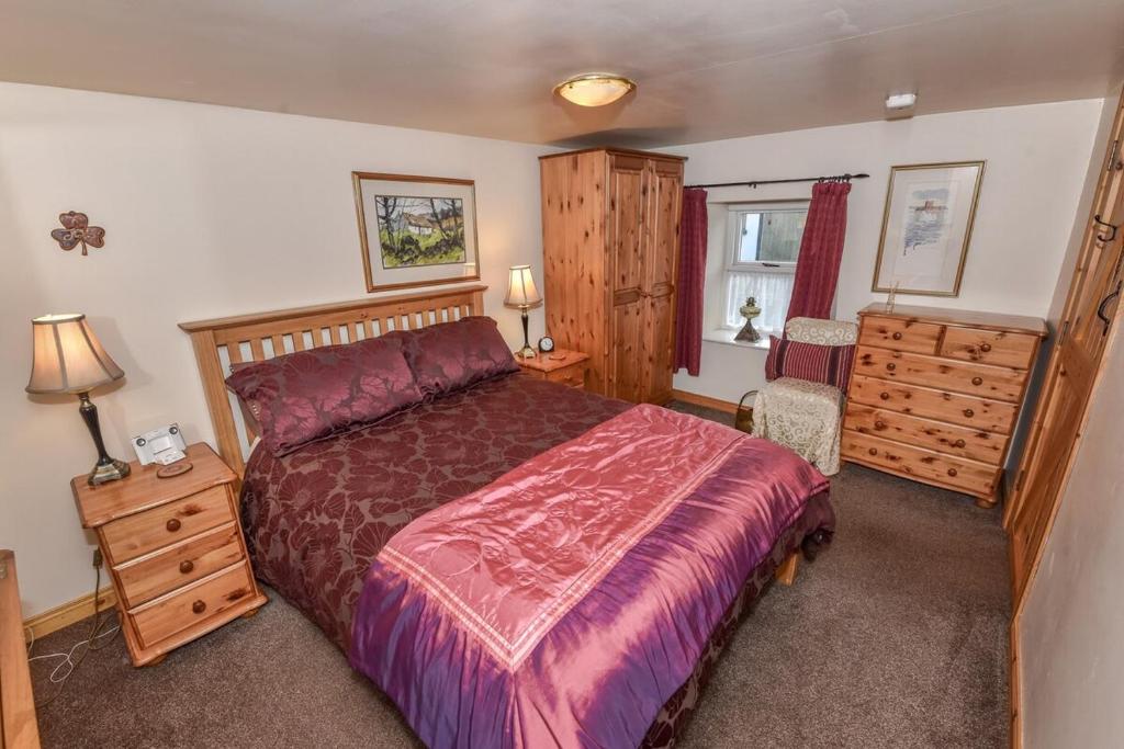 ein Schlafzimmer mit einem Bett, einer Kommode und einem Fenster in der Unterkunft Last-Minute Escapes l Sleeps Up to 4 l A delightful thatched cottage with all the modern facilities you will require l There are 2 bedrooms, one with a double bed l the other with two singles l Carrick Thatched Cottage l WeStayBelfast in Eden
