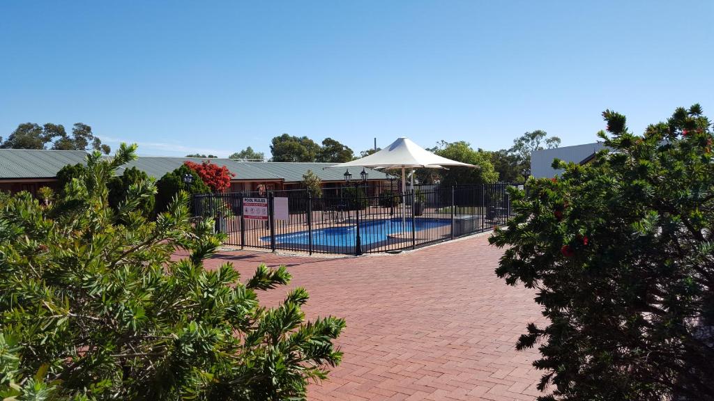 una piscina con recinzione e ombrellone di Gateway Motor Inn - Self Check-In a Broken Hill