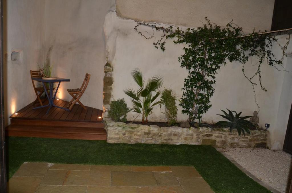 un patio avec une table et quelques plantes sur le mur dans l'établissement Maison en coeur de ville, à LʼIsle-sur-la-Sorgue