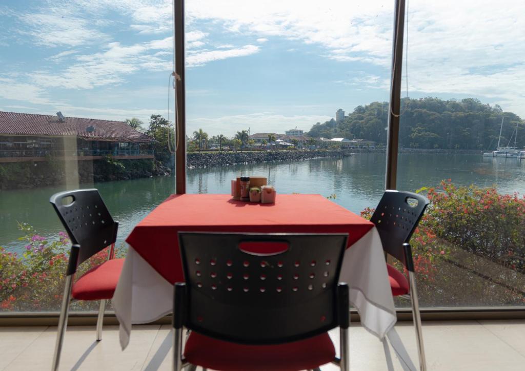 a red table and chairs with a view of a river at The Beach House in Panama City