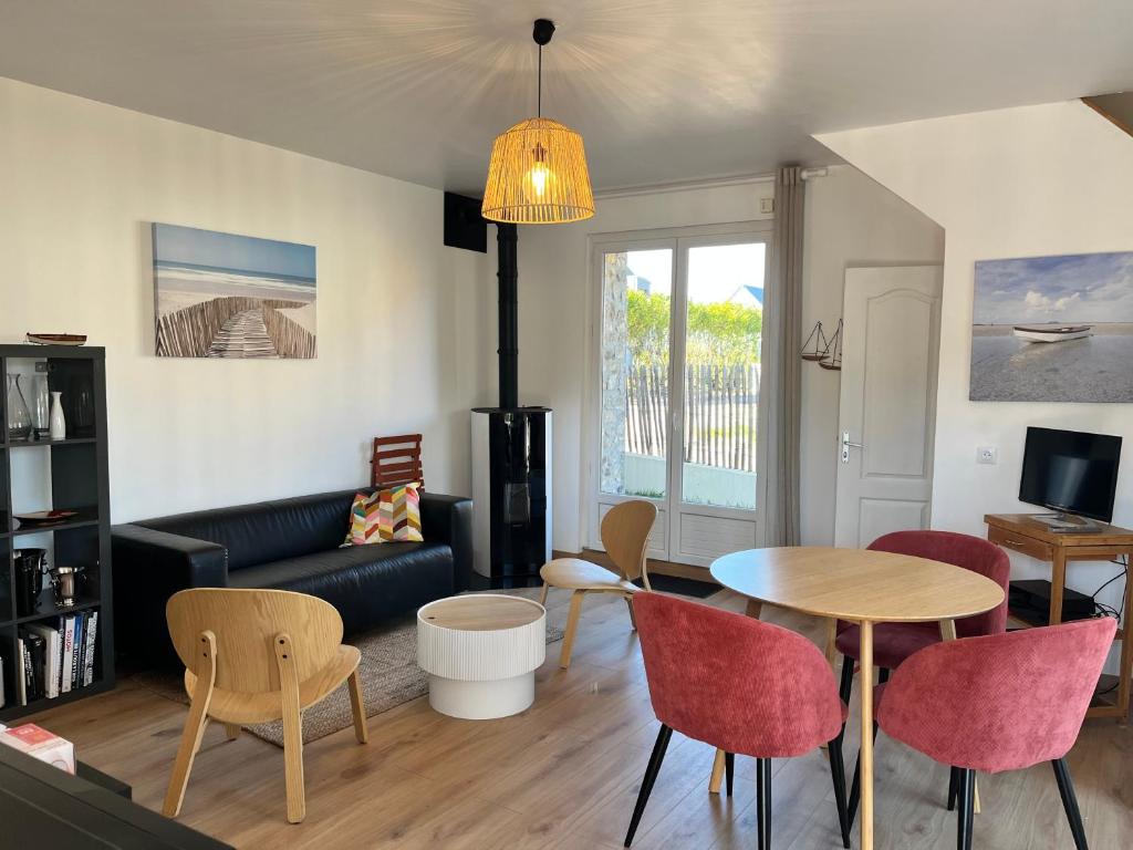 ein Wohnzimmer mit einer Couch und einem Tisch und Stühlen in der Unterkunft Maison rénovée à Agon-coutainville proche de la mer, classé meublé de tourisme 3 étoiles in Agon Coutainville