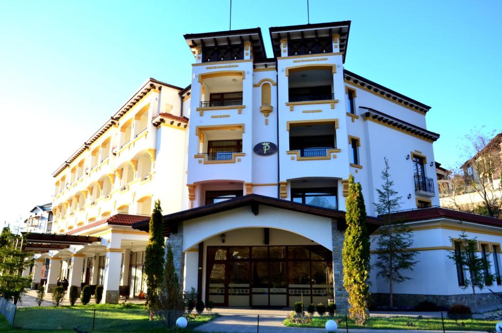 um grande edifício branco com árvores em frente em Hotel Paradise em Ognyanovo