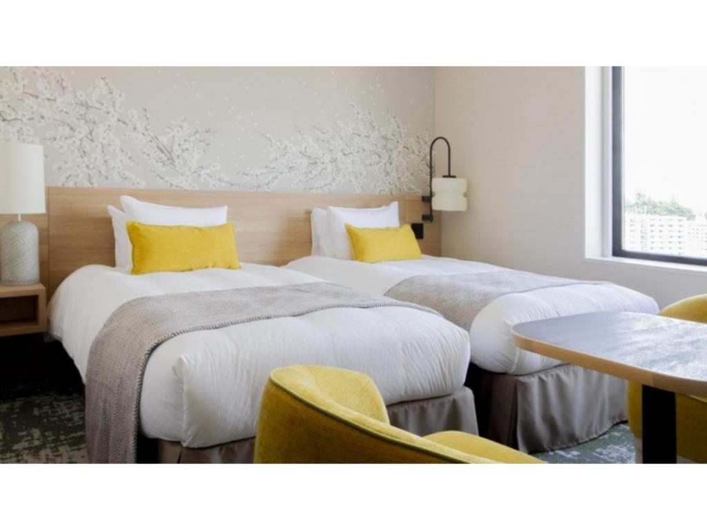 two beds in a hotel room with yellow pillows at Hotel Terrace the Garden Mito - Vacation STAY 75714v in Mito